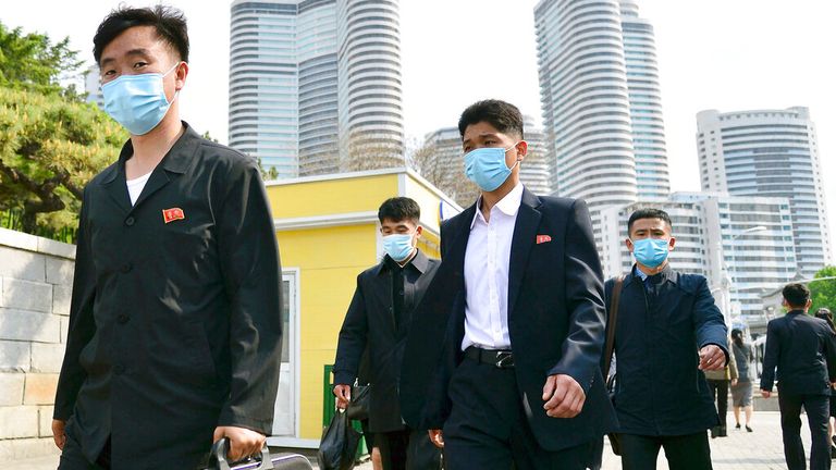 People wearing face masks walk in Pyongyang on 6 May 2022