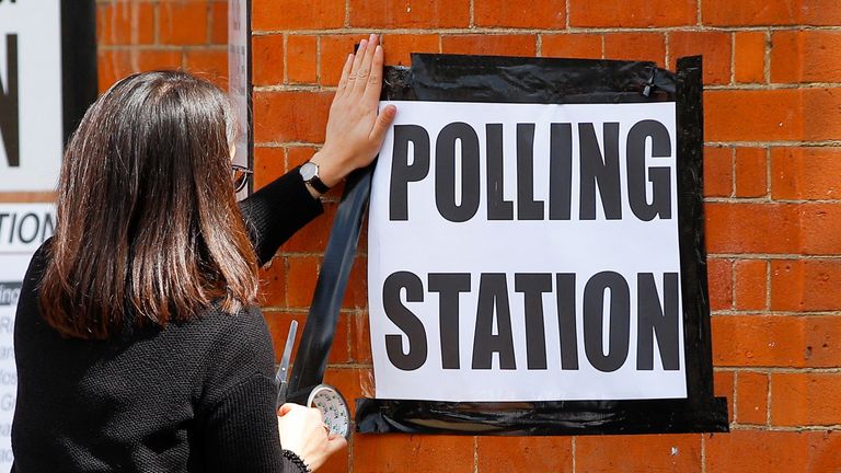 A woman attaches a sign on the wall of a polling station, during the local elections in London, Britain May 5, 2022. REUTERS/Peter Nicholls
