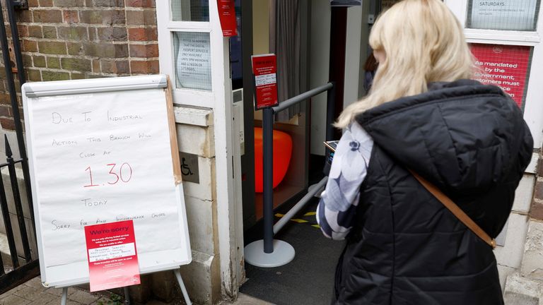 A woman walks past a sign informing customers of a Post Office branch closure due to industrial action, in St Albans, Britain, May 3, 2022. REUTERS/Peter Cziborra
