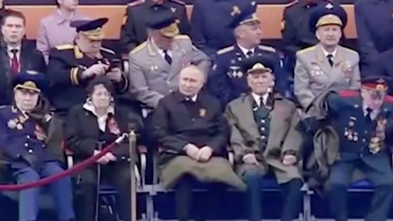 Vladimir Poutine avec quelque chose couvrant ses genoux, alors qu'il regarde le défilé pendant le Jour de la Victoire