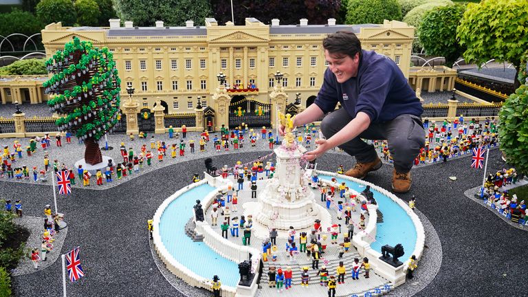 A member of the LEGOLAND Windsor staff makes adjustments to a LEGO replica of the Queen Victoria Memorial set in front of a LEGO replica of Buckingham Palace. LEGOLAND Windsor Resort today unveiled its royal-inspired models to celebrate The Queen&#39;s Platinum Jubilee. The overall number of bricks used was 18,001 and the models took a total of 281.5 hours to finish. The display also includes includes a street party and picnic scene as well as miniature versions of the royals, the tree of trees and 