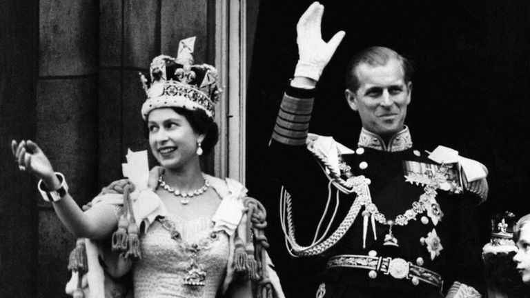 Queen Elizabeth II, wearing the Imperial State Crown, and the Duke of Edinburgh, dressed in uniform of Admiral of the Fleet, wave from the balcony to the onlooking crowds at the gates of Buckingham Palace after the Coronation.
