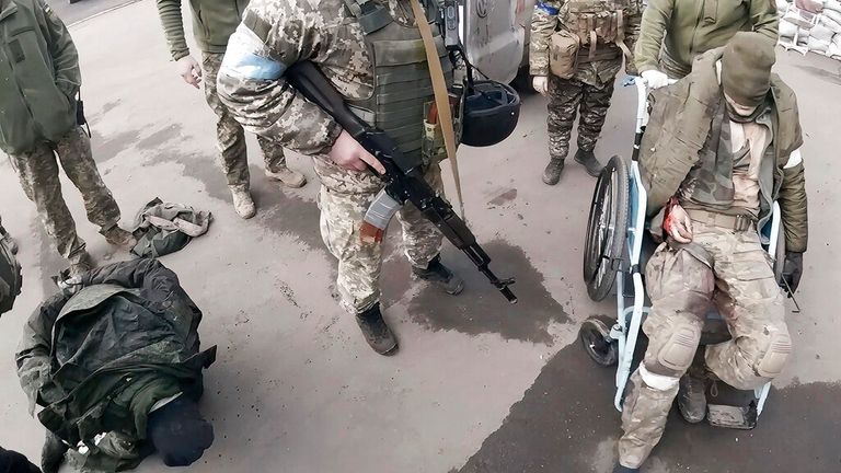 Two injured Russian soldiers, left and right, arrive at a hospital to be treated in Mariupol