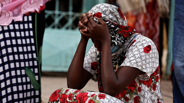 Kaba, a mother of a ten-day-old baby, reacts as she sits outside the hospital