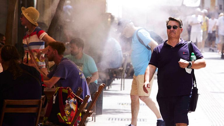 Un hombre pasa bajo los aspersores instalados en un bar de Sevilla.  Foto: AP