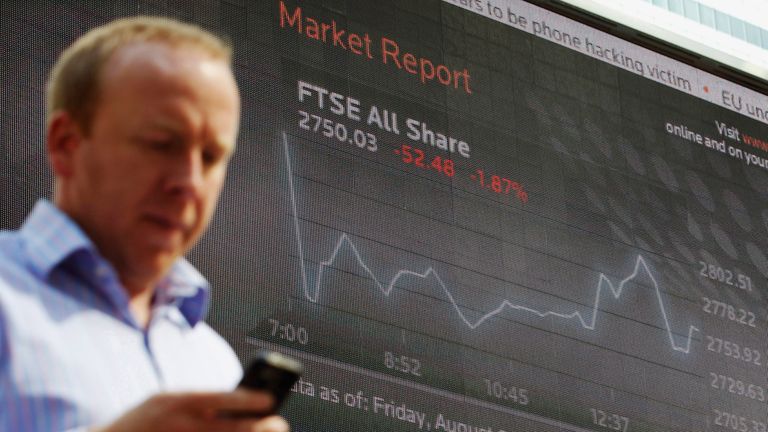 A man passes a screen showing the activity of the FTSE index at Canary Wharf financial district in London August 5, 2011. Banks and commodity stocks fell sharply on Friday as Britain&#39;s top share index extended losses into a sixth straight trading day, roiled by a global debt crisis and unmoved by U.S. jobs data easing fears of another economic recession. 