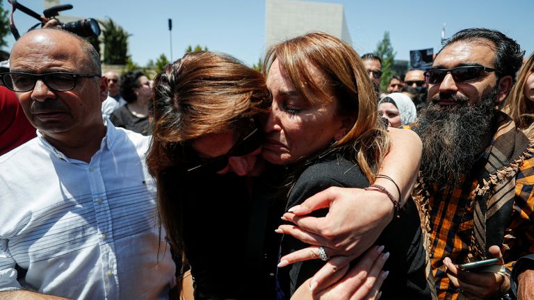 Des collègues s'embrassent alors qu'ils font leurs adieux à la journaliste d'Al Jazeera Shireen Abu Akleh, qui a été tuée lors d'un raid israélien, à Ramallah, en Cisjordanie occupée par Israël, le 12 mai 2022. REUTERS/Mohamad Torokman REFILE - RÉPÉTITION DE QUALITÉ