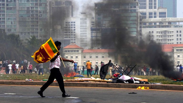 A Sri Lankan government supporter carries a national flag after attacking the anti-government protesters outside president&#39;s office in Colombo
PIC:AP