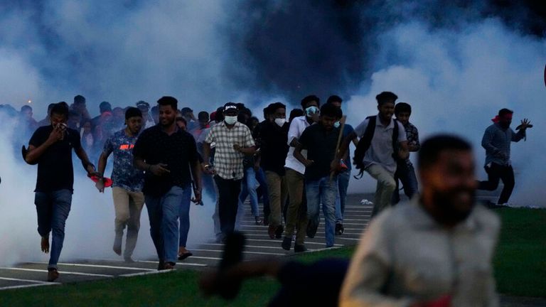 Sri Lankan students flee tear gas during a protest outside parliament in the capital
