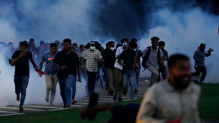 Sri Lankan students run from tear gas during a protest outside parliament in the capital