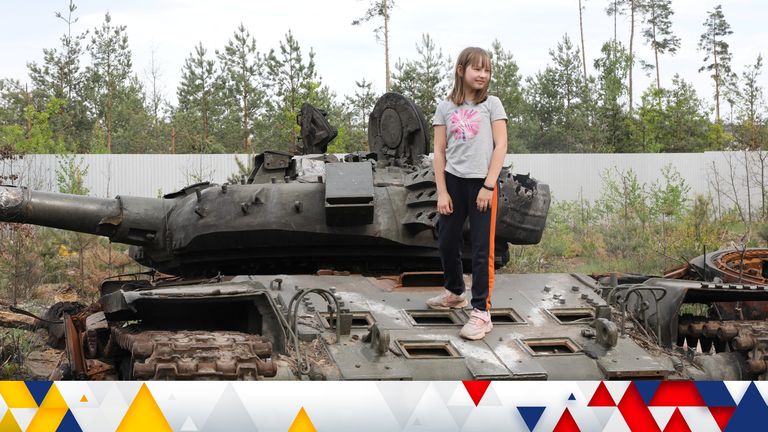 A girl stands on a destroyed Russian tank in the village of Dmytivka, as Russia&#39;s attack on Ukraine continues, in Kyiv region, Ukraine May 20, 2022. REUTERS/Marius Bosch