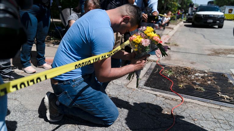 Joseph Avila, left, prays while holding flowers honoring the victims killed in Tuesday...s shooting at Robb Elementary School in Uvalde, Texas, Wednesday, May 25, 2022. Desperation turned to heart-wrenching sorrow for families of grade schoolers killed after an 18-year-old gunman barricaded himself in their Texas classroom and began shooting, killing at least 19 fourth-graders and their two teachers. (AP Photo/Jae C. Hong)