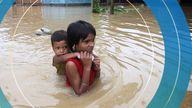 A girl carries her brother as she wades through a flooded road after heavy rains, on the outskirts of Agartala, India, June 18, 2022. 