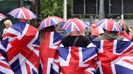 People wrapped in Union Jack flags pose as they gather on The Mall ahead of a concert outside Buckingham Palace during Britain&#39;s Queen Elizabeth&#39;s Platinum Jubilee celebrations, in London, Britain, June 4, 2022. REUTERS/Phil Noble