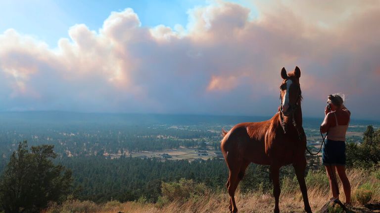 Janetta Kathleen and her horse, Squish, watch as smoke rises above neighborhoods on the outskirts of Flagstaff, Ariz., Sunday, June 12, casts a glow above neighborhoods. Evacuations have been ordered for homes in the area. Authorities say firefighters are responding to the wildfire about six miles north of Flagstaff that has forced evacuations. (AP Photo/Felicia Fonseca)