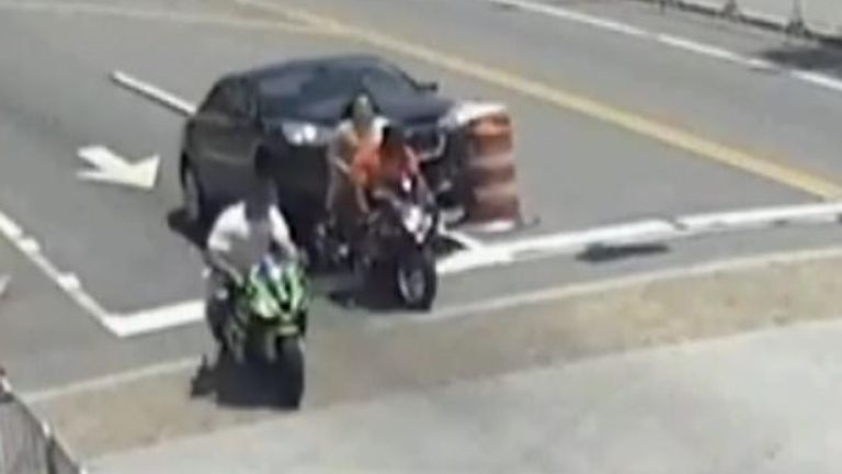 Dramatic footage released by police shows onlookers coming to the rescue of a motorcyclist trapped beneath a car.