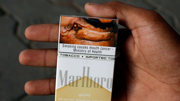 Bir adam, Pakistan'ın Karaçi kentinde bir yol üzerindeki bir büfede sağlık uyarısı gösteren Philip Morris markasına ait bir paket Marlboro sigarasını tutuyor 5 Mayıs 2018. Fotoğraf 5 Mayıs 2018'de çekildi. REUTERS/Akhtar Soomro