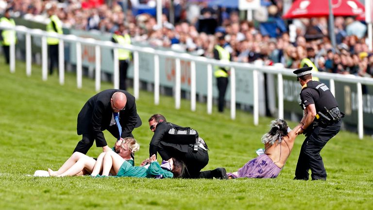 Horse Racing - Derby Festival - Epsom Downs Racecourse, Epsom, Britain - June 4, 2022 Protesters are detained by police officers ahead of the Cazoo Derby REUTERS/Andrew Boyers
