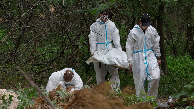 Forensic technicians carry a body of a person who, as Ukrainian police say, was killed and buried at a position of Russian troops during Russia&#39;s invasion, near the village of Vorzel in Bucha district, Kyiv region, Ukraine June 13, 2022. REUTERS/Valentyn Ogirenko
