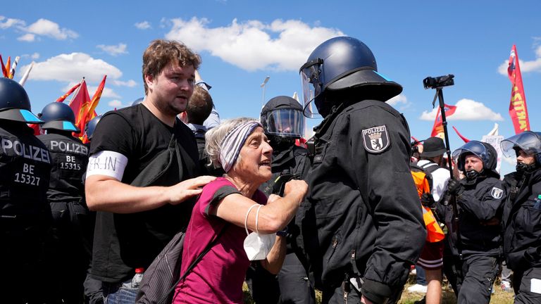 A woman walks by a police officer during scuffles between police and protestors at a demonstration ahead of a G7 summit in Munich, Germany, Saturday, June 25, 2022. The G7 Summit will take place at Castle Elmau near Garmisch-Partenkirchen from June 26 through June 28, 2022. (AP Photo/Matthias Schrader)