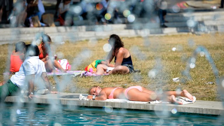 People relax by a pool at Marble Arch, in central London July 18, 2013. The Met Office raised its heatwave warning for south-west England and the West Midlands to "level three", local media reported. REUTERS/Paul Hackett (BRITAIN - Tags: CITYSCAPE ENVIRONMENT)
