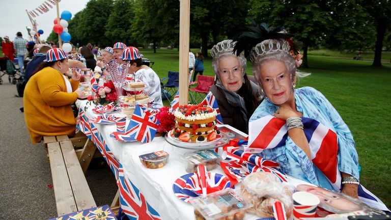 People dressed in outfits with a Union Jack theme and masks depicting Britain&#39;s Queen Elizabeth gather around a picnic table as they take part in the Big Jubilee Lunch on The Long Walk as part of celebrations marking the Platinum Jubilee of Britain&#39;s Queen Elizabeth, in Windsor, Britain, June 5, 2022. REUTERS/Peter Nicholls 