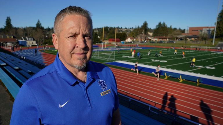 Joe Kennedy, a former assistant football coach at Bremerton High School in Bremerton, Wash., poses for a photo March 9, 2022, at the school&#39;s football field. After losing his coaching job for refusing to stop kneeling in prayer with players and spectators on the field immediately after football games, Kennedy will take his arguments before the U.S. Supreme Court on Monday, April 25, 2022, saying the Bremerton School District violated his First Amendment rights by refusing to let him continue pra