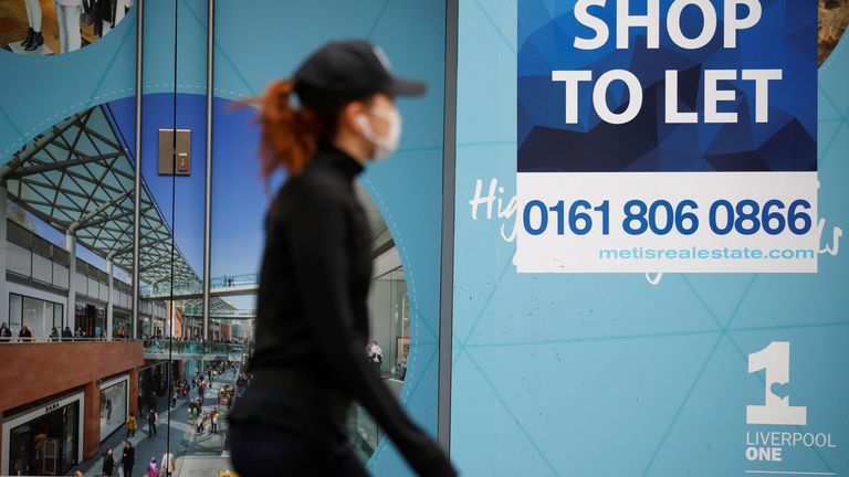 A woman wearing a face mask walks by a "Shop To Let" sign in a window in Liverpool, following the outbreak of the coronavirus disease (COVID-19), Liverpool, Britain, May 26, 2020. REUTERS/Phil Noble
