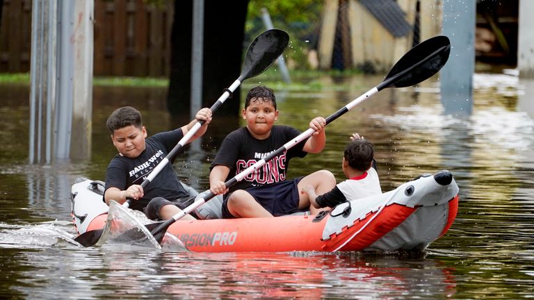 Young boys paddle an inflatable kayak on a flooded Miami street, Saturday, June 4, 2022. Pic: AP