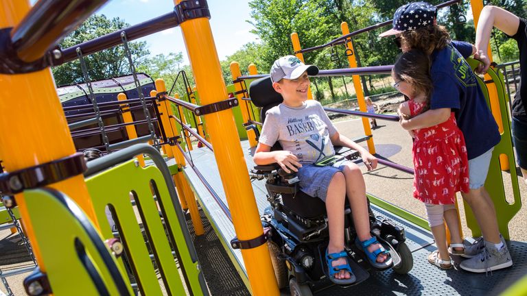 ADVANCE FOR USE WEEKEND EDITIONS, JULY 9-10 - In this photo taken June 22, 2016, children step to the side of a ramp as Ben Anco drives his wheelchair around Madison&#39;s Place playground in Woodbury, Minn. &#34;He gets to be a real kid,&#34; his mom, Page Laska, said about being able to take Ben to a fully accessible playground. (Evan Frost/Minnesota Public Radio via AP)