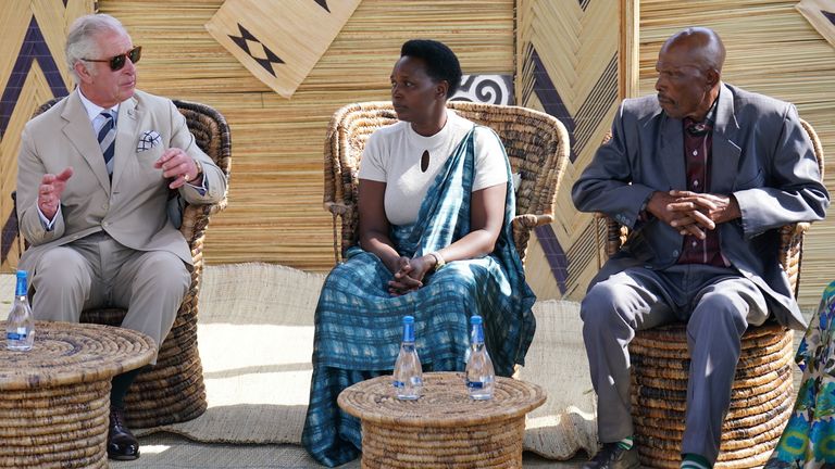 Prințul de Wales ascultă o victimă a genocidului (centru) și un făptuitor care a fost grațiat (dreapta) relatând experiențele lor în timpul vizitei sale în satul de reconciliere Mybo din Nyamata, ca parte a vizitei sale în Rwanda.  Data fotografiei: miercuri, 22 iunie 2022.