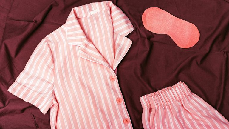 Warm pink kit for sleeping.  Soft cotton t-shirt and shorts. Comfortable clothes for healthy sleep. Pajamas are neatly complicated on bed. Top view. Flat lay. 