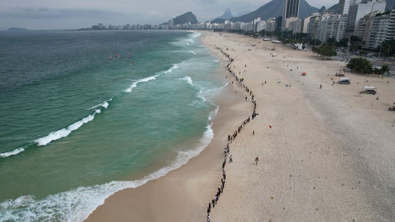 People create a line along Copacabana beach for a symbolic group hug with the sea on World Oceans Day in Rio de Janeiro, Brazil, Wednesday, June 8, 2022. The Route Brasil organization called for people to gather for the event coined &#34;That Hug,&#34; and to pick up trash on the beach, to draw the attention to ocean pollution. (AP Photo/Silvia Izquierdo)