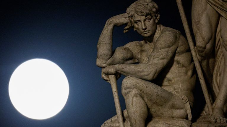 The full moon, also known as the Supermoon or Strawberry Moon, rises behind a statue in Rome, Italy, June 14, 2022. REUTERS/Guglielmo Mangiapane