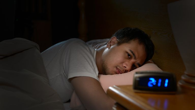 Depressed man suffering from insomnia lying in bed