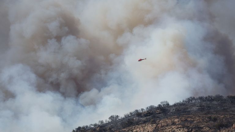 A helicopter flies next to a smoke during a wildfire near Artesa de Segre, Spain, June 18, 2022. REUTERS/Albert Gea
