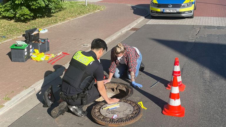 25 June 2022, Police officers examine a storm drain 