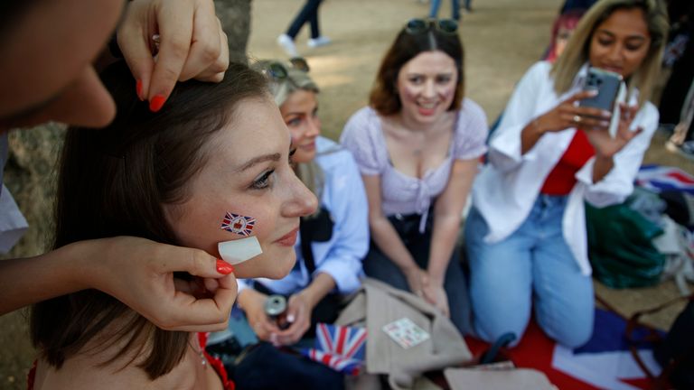 Royal fans have Union flag transfers applied to their faces as they gather along the Mall leading to Buckingham Palace in London, Thursday June 2, 2022, on the first of four days of celebrations to mark the Platinum Jubilee. The events over a long holiday weekend in the U.K. are meant to celebrate the monarch&#39;s 70 years of service. (AP Photo/David Cliff)