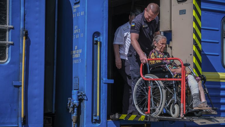 A woman is loaded on to a train at a station in east Ukraine