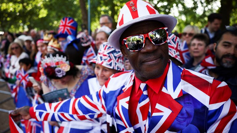 Un uomo in una tuta Union Jack guarda mentre le persone si riuniscono lungo il Mall per celebrare il Queen's Platinum Jubilee a Londra, Gran Bretagna, 2 giugno 2022. REUTERS/Henry Nichols