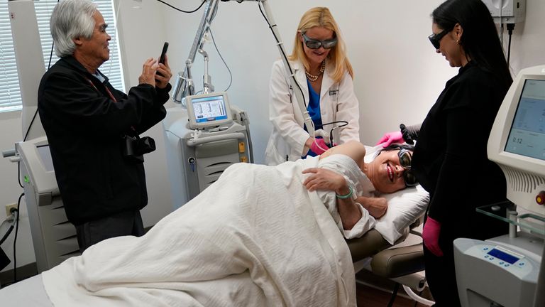 Retired Associated Press photographer Nick Ut, left, takes photographs as Kim Phuc, second from right, receives a laser treatment by Dr. Jill Waibel, second from left, at the Miami Dermatology and Laser Institute, Tuesday, June 28, 2022, in Miami. Phuc was the subject 50 years ago of the Pulitzer Prize-winning "Napalm Girl" photo by AP photographer Ut. She has been treated since 2015 pro bono at the institute for scars suffered in the June 8, 1972, firebombing of her village during the Vietnam War. Ut and Kim maintain a close friendship. At right is Bianka Hinkle. (AP Photo/Lynne Sladky)