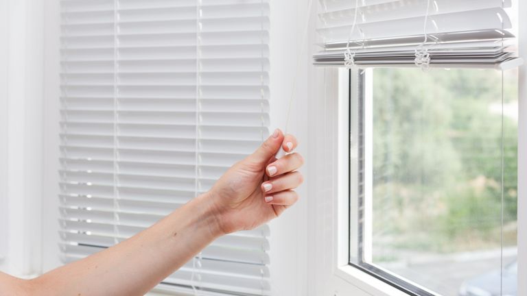 Adjusting the white blinds in height use a cord