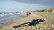 French police officers pass a deflated dighy on the beach in Wimereux near Calais as migrants continue to launch small boats along the coastline in a bid to cross the Channel towards the UK. Picture date: Thursday November 18, 2021.
