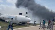 Firefighters spray water on a plane that flipped over after a crash landing, in Mogadishu, July 18, 2022, in this screen grab obtained from a social media video obtained by Reuters. 