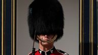 A British soldier wearing a traditional bearskin hat, stands with sweat on his face whilst on guard duty outside Buckingham Palace, during hot weather in London, Monday, July 18, 2022