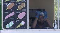 An ice cream vendor uses a bottle of water to cool down during hot weather in Hyde Park in London, Britain, July 19, 2022. REUTERS/Toby Melville
