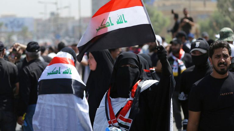 A protester holds an Iraqi flag as people gather near the Green Zone area in Baghdad Pic: AP 