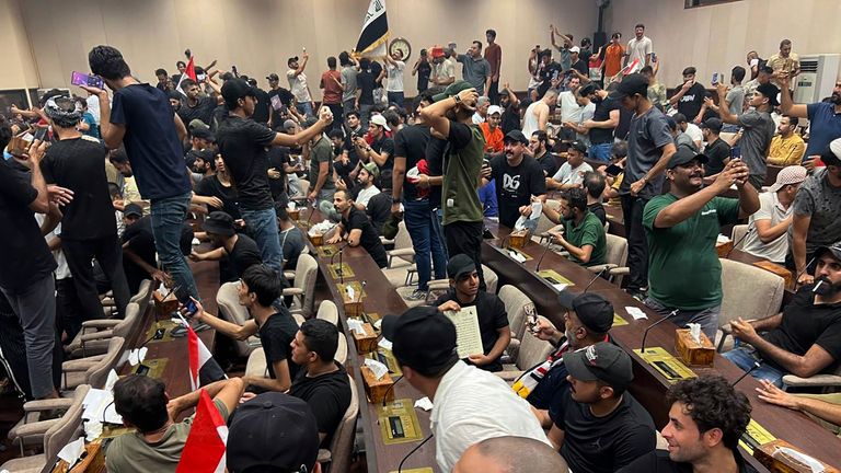 Iraqi protesters breach Baghdad&#39;s parliament in Baghdad, Iraq, Wednesday, July. 27, 2022.  The majority of the protesters were followers of influential Shiite cleric Muqtada al-Sadr. The demonstrators, all of them men, were seen walking on tables of the parliament floor, sitting in the chairs of lawmakers and waving Iraqi flags.   (AP Photo/Ali Abdul Hassan)