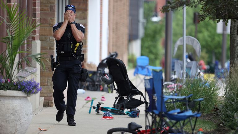     A Lake Forest, Illinois, police officer walks along Central Ave in Highland Park, Illinois on Monday, July 4, 2022, after a shooter fired at the northern suburb's 4th of July parade.  (Brian Cassella / Chicago Tribune via AP)
