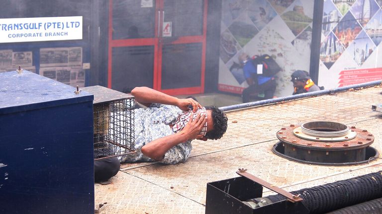 一名男子在斯里兰卡首都发射催泪瓦斯后捂住脸。 图片：美联社